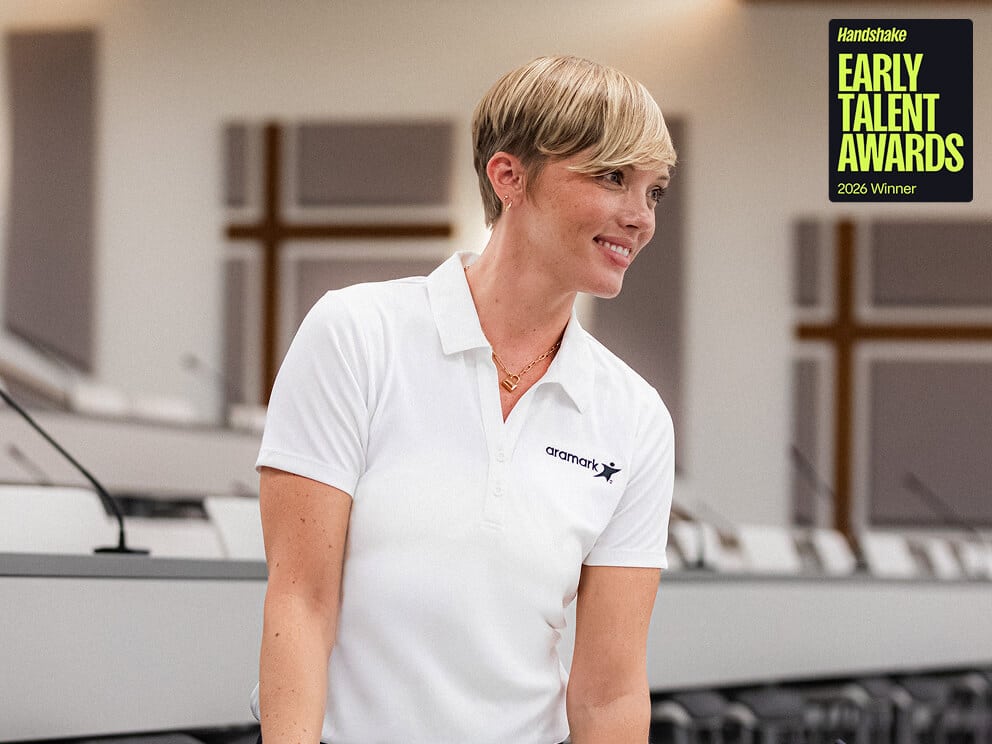Smiling Aramark employee in a white polo, with a Handshake Early Talent Awards 2026 Winner badge overlay