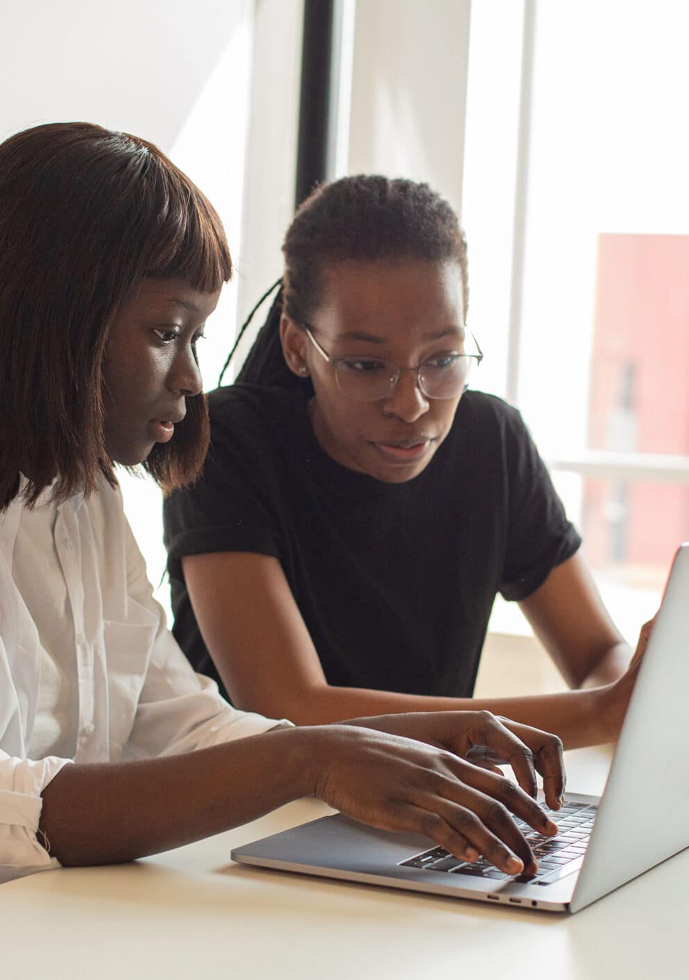 Two women closely reviewing something together on a laptop screen