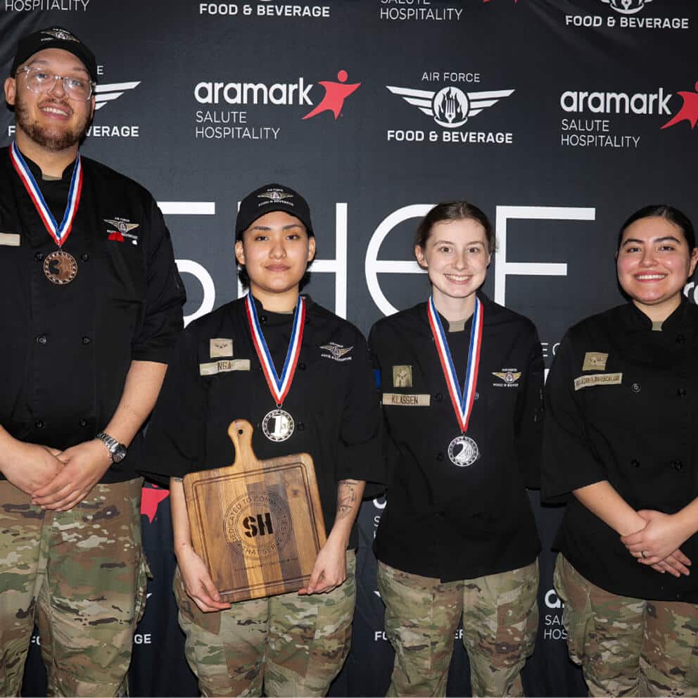 Four Air Force chefs wearing medals pose with an award plaque at the Aramark Salute Hospitality culinary competition